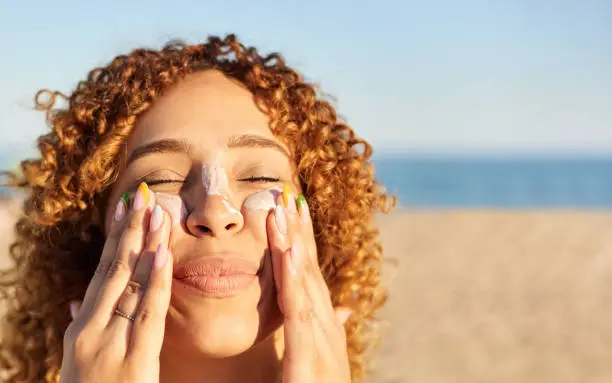 Person applying sunscreen to face in natural daylight