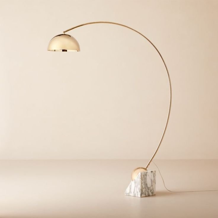 A curved floor lamp Venus-Champagne-Brass-Arc-Floor-Lamp-with-White-Marble-Base